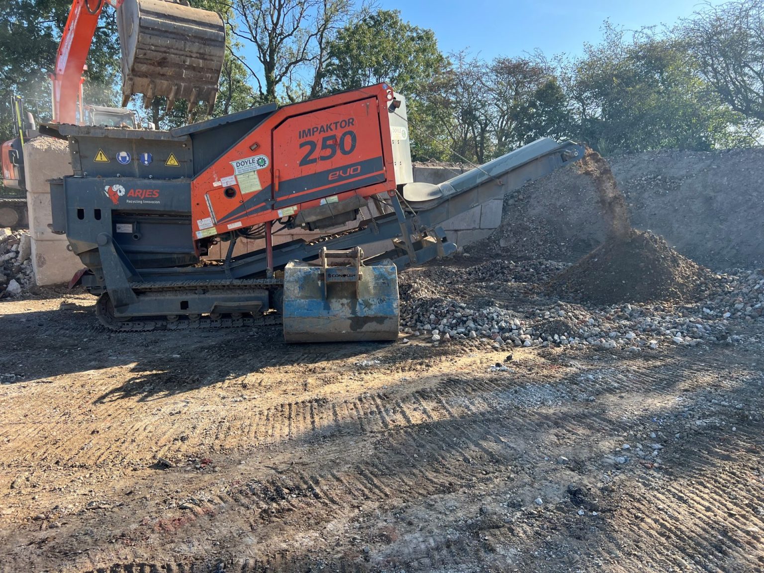 Orange Dirtec 290 tracked shredder processing material on a demolition site